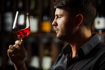 Bokal of red wine on background, male sommelier appreciating drink