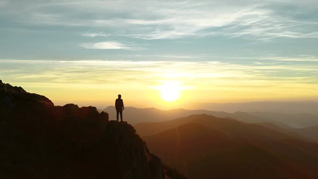 The male standing on the mountain and enjoying the beautiful sunset