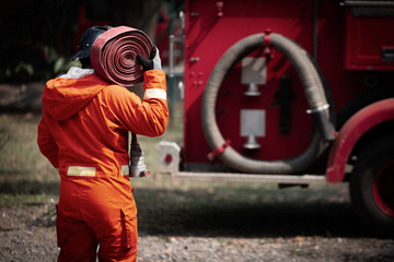 Firefighters training, Team practice to fighting with fire in emergency situation. A fireman carry a water hose run through flame