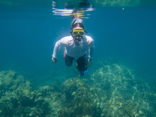 Underwater shoot of a young man in white shirt snorkeling in a tropical sea. vacation concept