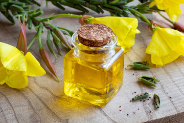 A bottle of evening primrose oil with evening primrose flowers and seeds