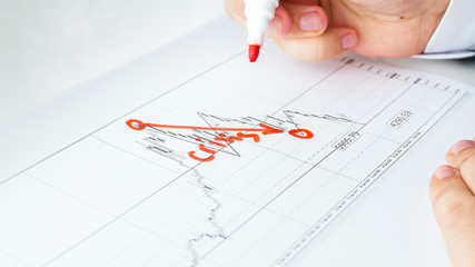Concept of financial crisis. Businessman drawing decreasing graph on financial data chart