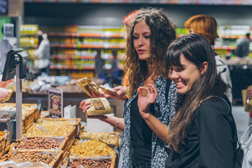 two women buying dried fruit in grocery store.
