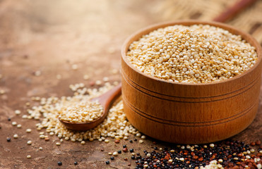 Quinoa. White quinoa grains in a wooden bowl. Healthy food. Dieting concept. Seeds of white, red and black quinoa - Chenopodium quinoa