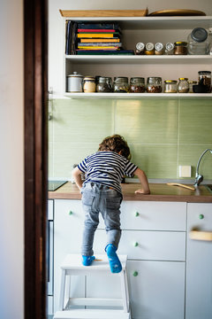 Little boy climbing on a countertop in his kitchen