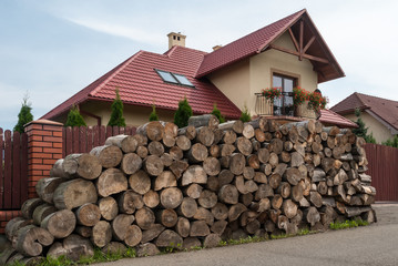 Masonry of round logs, sawn and stacked, in the background of the house
