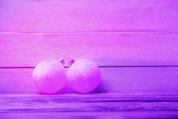 Two violet Christmas balls over wooden background.