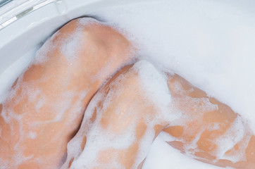 Female feet in soap bath, skin care and epilation concept image. Part of body, selective focus