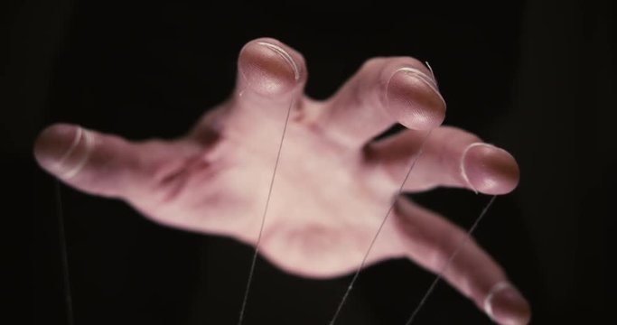 Closeup of a puppet hand with string tied around the fingers