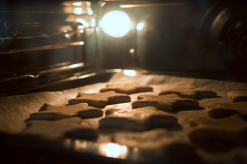 Christmas cookies baking in the oven. Christmas baking. Gingerbread biscuits on baking tray. - obrazy, fototapety, plakaty