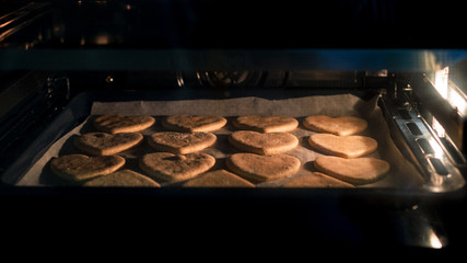 Christmas cookies baking in the oven. Christmas baking. Gingerbread biscuits on baking tray.