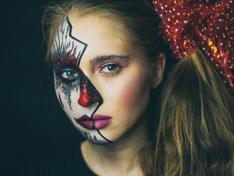 Portrait of a girl in makeup. Halloween, the face of a girl is a doll, the floor of a face is dead.