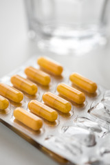 Pillen Blister mit gelben Kapsel Tabletten und Wasser Glas