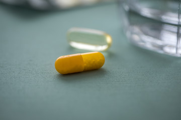 Zwei Gelbe Pillen Kapsel Medikament und Blister mit Glas Wasser