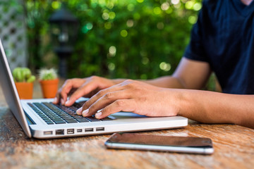 Close up man hands typing laptop computer on wood table.