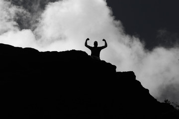 Self empowerment and success with mans sillhouette on top of mountain.