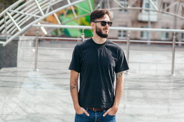 A stylish man with a beard  with a black T-shirt. Street photo