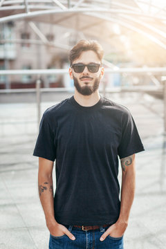 A stylish man with a beard  with a black T-shirt. Street photo