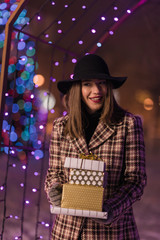 Young girl holding presents for Christmas alone in the park waiting