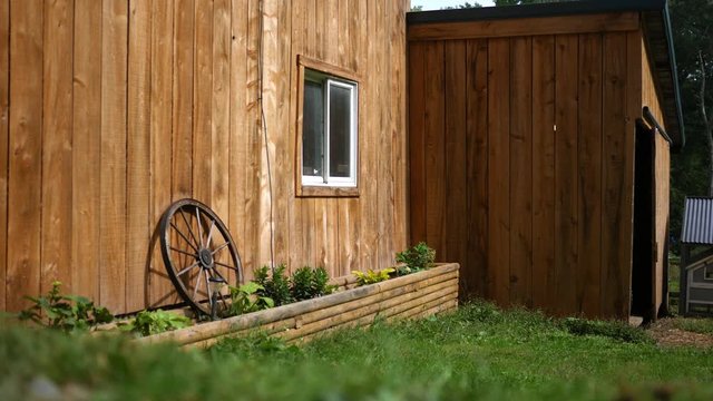 An establishing shot of a wooden barn with cat running beside frame