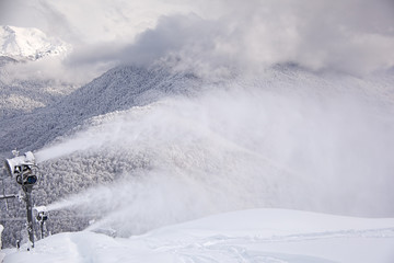 Snow gun on the background of the Caucasus mountains that shoot artificial snow