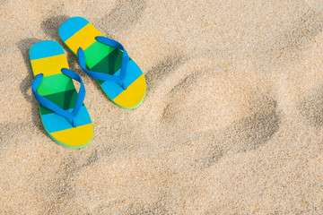 Beach sandals on the sandy coast for background summer concept.
