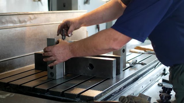 Male specialist borer fixes a metal pulley on a reaming machine, small business, workroom, gin
