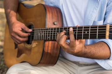 Obraz premium Młody przystojny mężczyzna Azji gra na gitarze w parku. Styl życia na świeżym powietrzu.