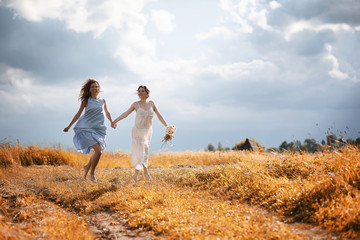 Fototapeta na wymiar Two girls in dresses in autumn field
