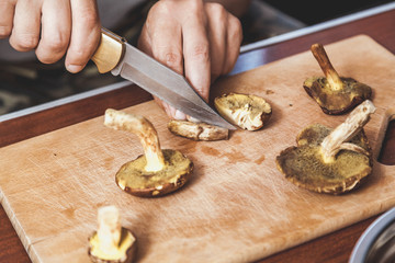 Hands cut raw mushrooms with sharp knife