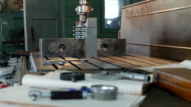 A private workshop for working with metal parts, in the background a drilling machine drills a hole in the pulley, on the table lie measuring instruments, mensuration