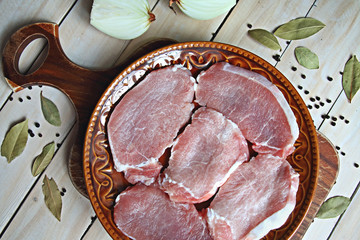 Close up of uncooked meat fillets on a brown plate over wooden background top view