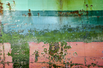 Old and weathered shiphull with layers of paint in different colors, patches of rust, welding...