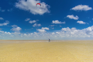 Kite surfer in the distance carrying his kite 