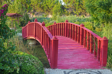 Red wooden bridge in the summer garden