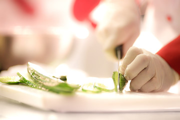 Chef Cutting cucumber on board