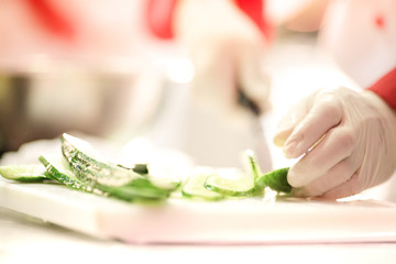 Obraz na płótnie Canvas Chef Cutting cucumber on board