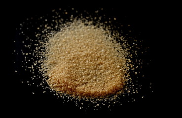 Brown sugar, pile isolated on black background, sugarcane