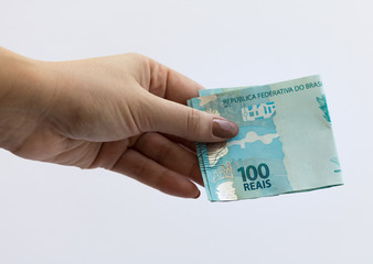 Female hand holding Real hundred note. Brazilian money. Selective focus. Brazilian currency. Economy, inflation, business. 100.