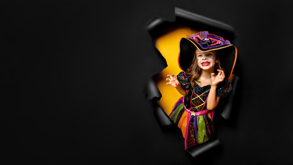 Happy Halloween. Laughing funny child girl in a witch costume of halloween looking, smiling and...