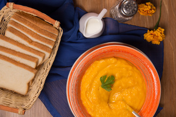 Pumpkin cream soup in a ceramic plate on the kitchen table