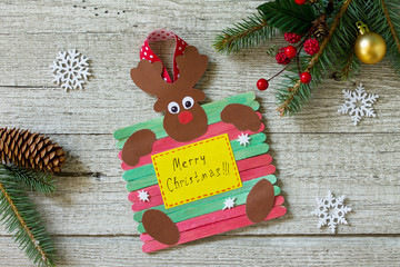 Reindeer stick gift on wooden table. Handmade. Project of children's creativity, handicrafts, crafts for kids.