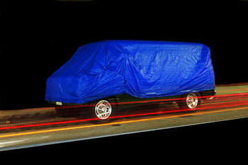 A view of a vintage van car and light trails in a black background