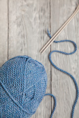 Fototapeta na wymiar blue ball of yarn with spokes on grey wooden background