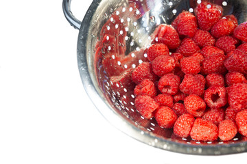 Delicious fresh and wet red raspberry in a colander for washing isolated at white background