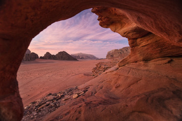view from natural cave to pink sky in sunset in desert