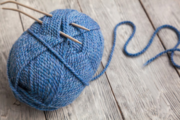 blue ball of yarn with spokes on grey wooden background