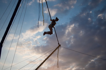 silhouette of a young girl jumping on a bungee on a trampoline on a sunset background on a sea