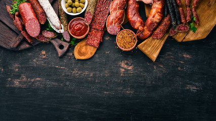 Assortment of salami and snacks. Sausage Fouet, sausages, salami, paperoni. On a black wooden background. Top view. Free space for your text.