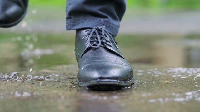 Man in black shoes stepping into the puddle in 4k slow motion 60fps